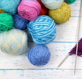 An assortment of balls of yarn with two knitting needles
