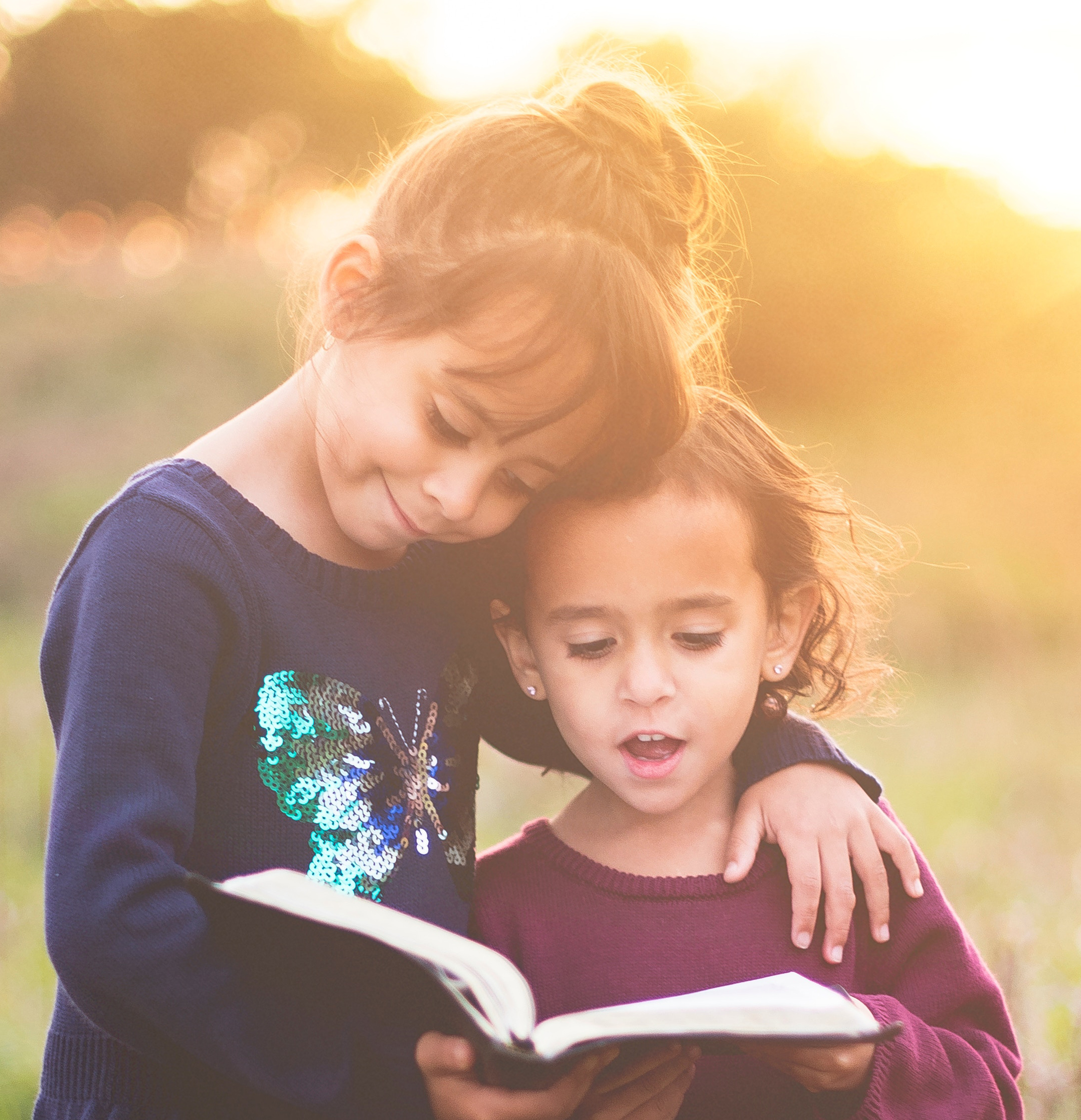 Two girls reading an open book together
