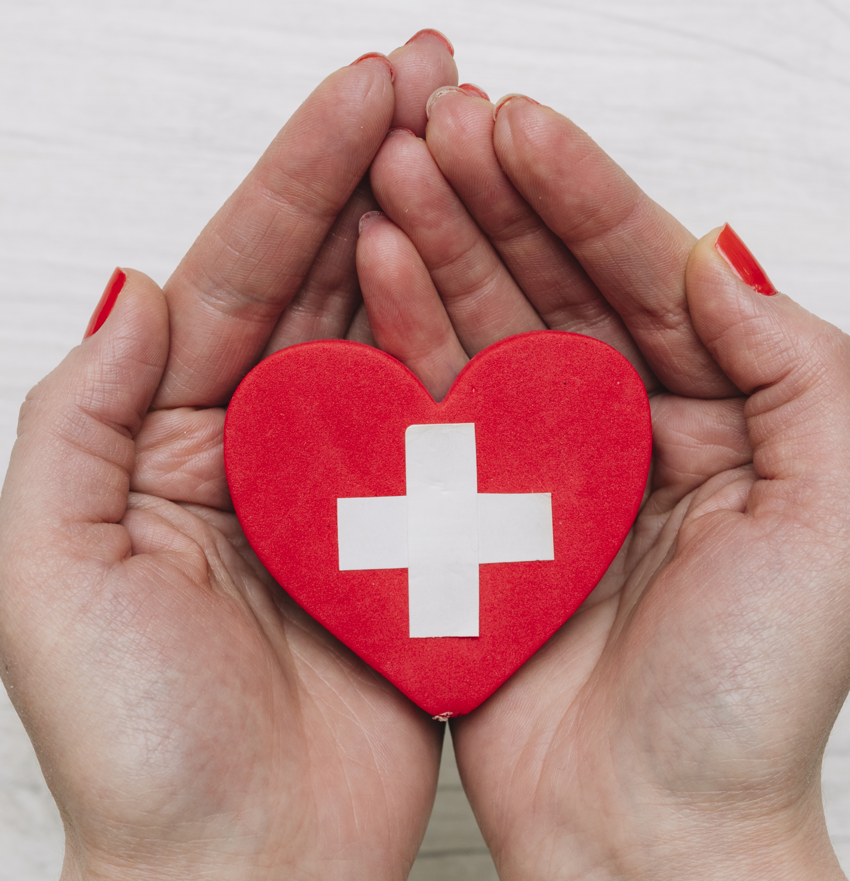 hands holding heart with first aid symbol