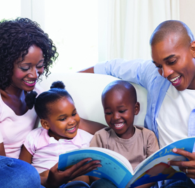 A mother and father reading a picture book with their daughter and son