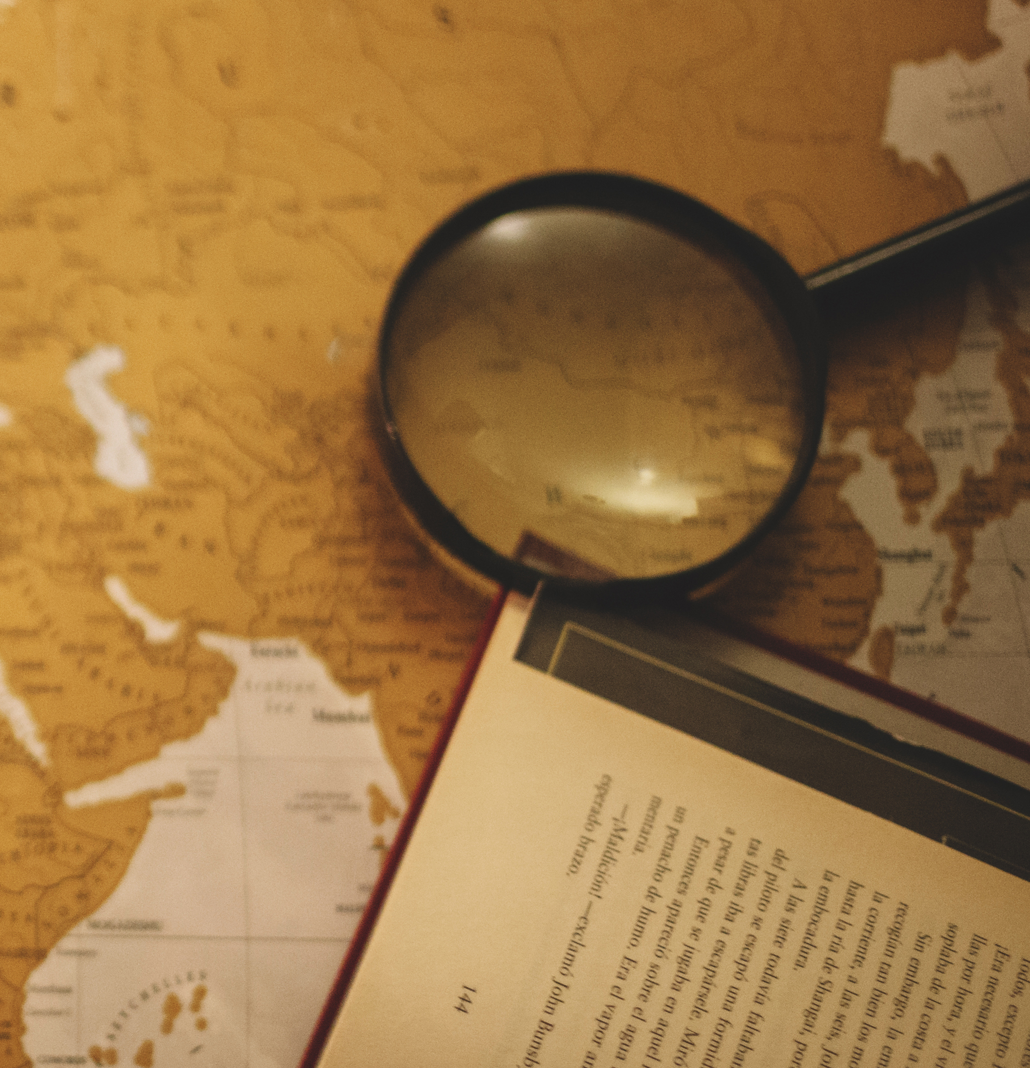 A photo of a map with a magnifying glass and open book
