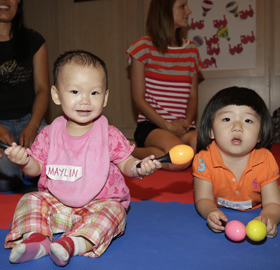 Two babies on the floor with rattles