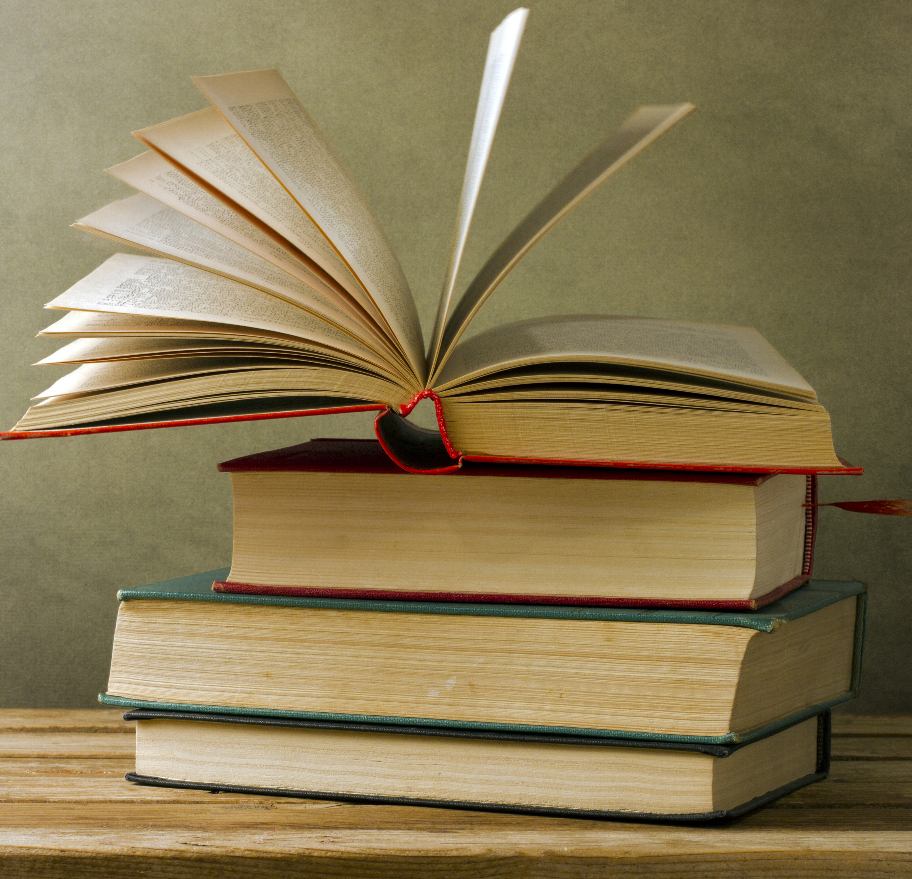 A photograph of a stack of books with the top one open
