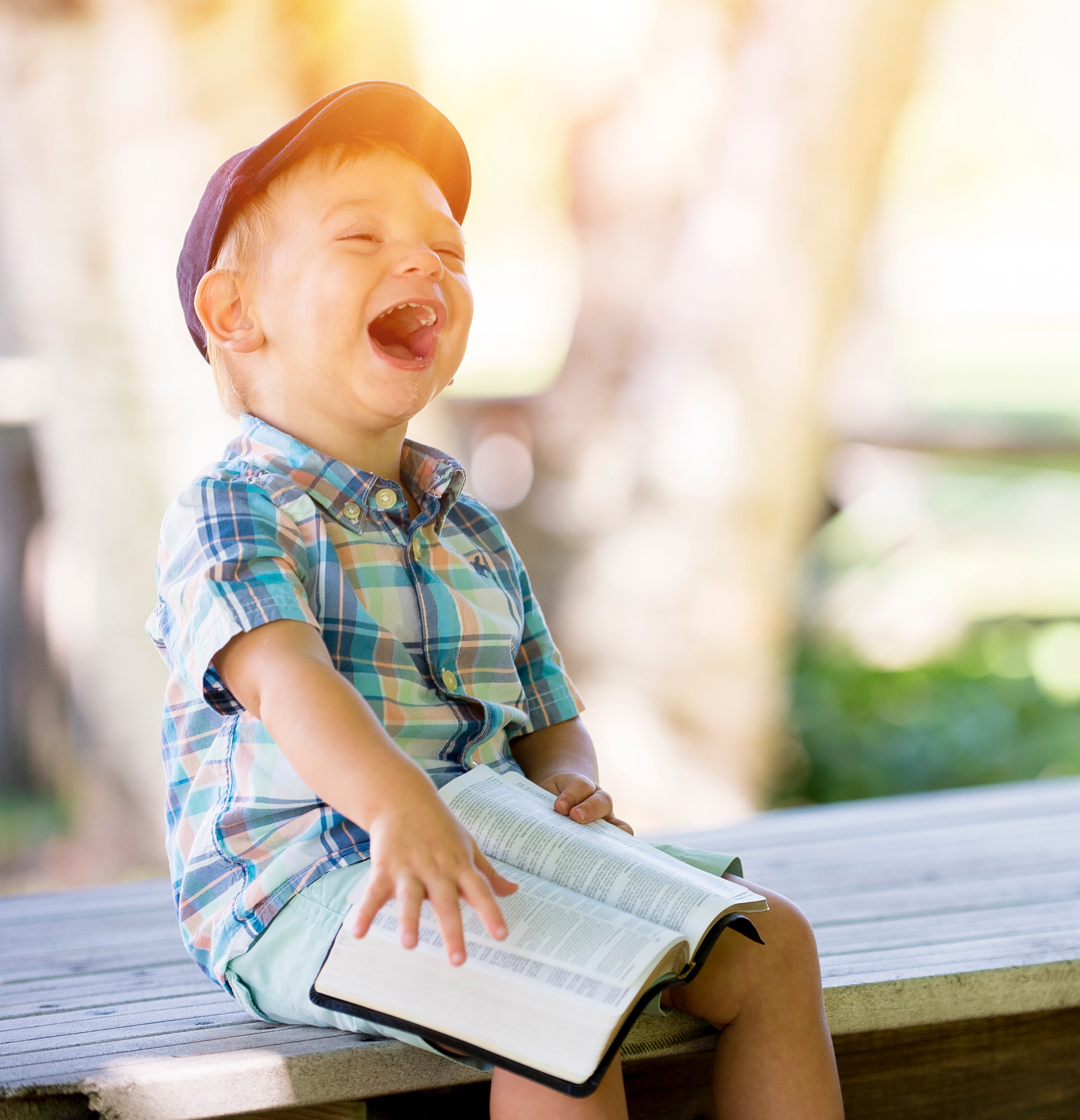 An image of a laughing child who is reading a book