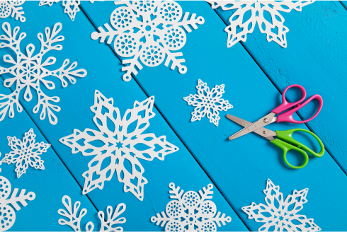 paper snowflakes on blue table with scissors