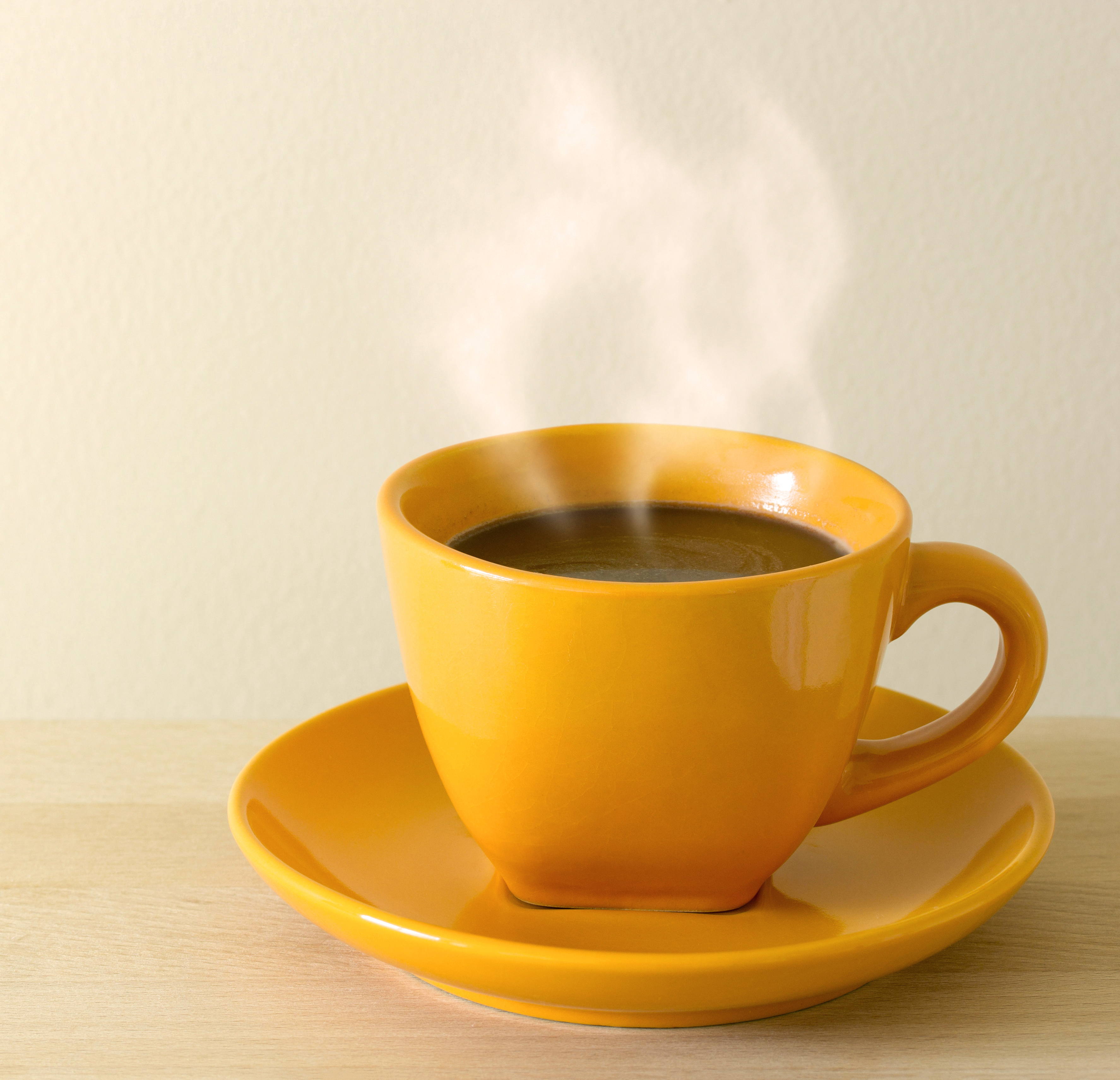 A yellow cup of coffee on a yellow saucer