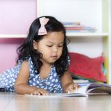 little girl with a book on the floor