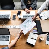 Image of people working at laptops on a shared desk