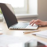 Image of hand typing on laptop