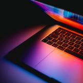 Partially closed laptop reflecting purple light