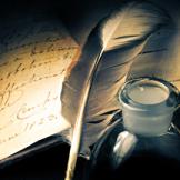 Photograph of a quill, a pot of ink and an open journal
