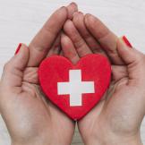 hands holding first aid symbol shaped like a heart