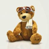 A stuffed brown teddy bear wearing goggles and a scarf