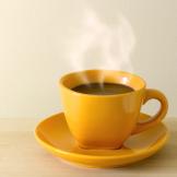 A yellow cup of coffee on a yellow saucer