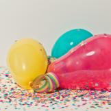 A yellow, turquoise and red balloon surrounded by confetti and ribbons