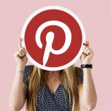 A woman holding up the Pinterest logo