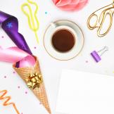 A photograph of a cup, streamers, confetti, scissors and a binder clip
