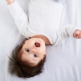 baby lying on back on sheet
