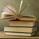 A photograph of a stack of books with the top one open