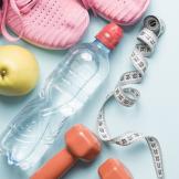 water bottle with running shoes, weights, and an apple