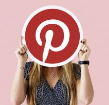 A woman holding up the Pinterest logo