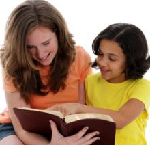 Two girls reading a book together